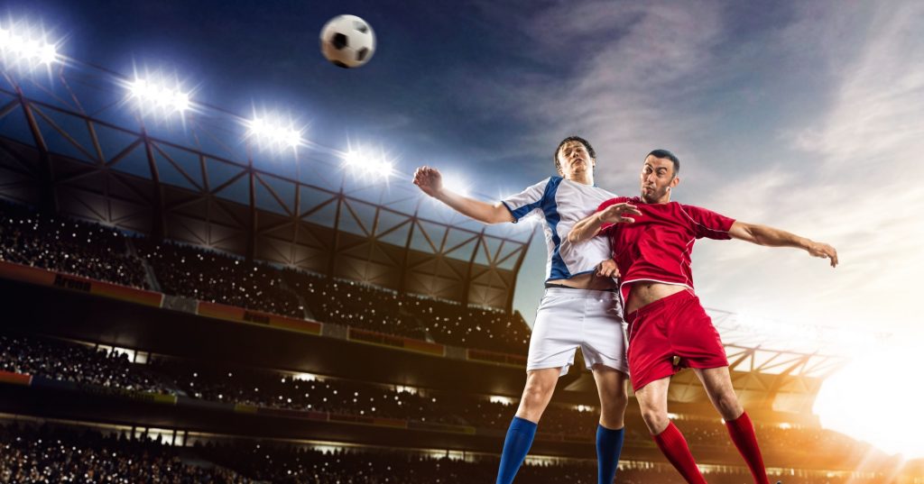 two footballers trying to hit a ball with their heads